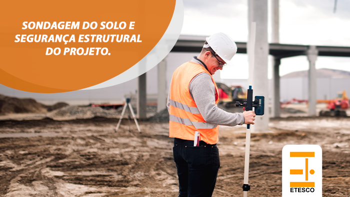 Profissional usa equipamento de medição em terreno de obra, realizando análise e sondagem do solo.